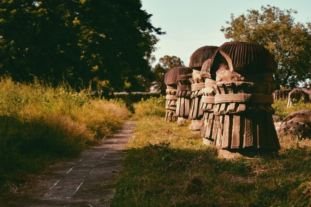 Carved stone pillars with rounded tops beside a path at the Kachari Ruins in Dimapur